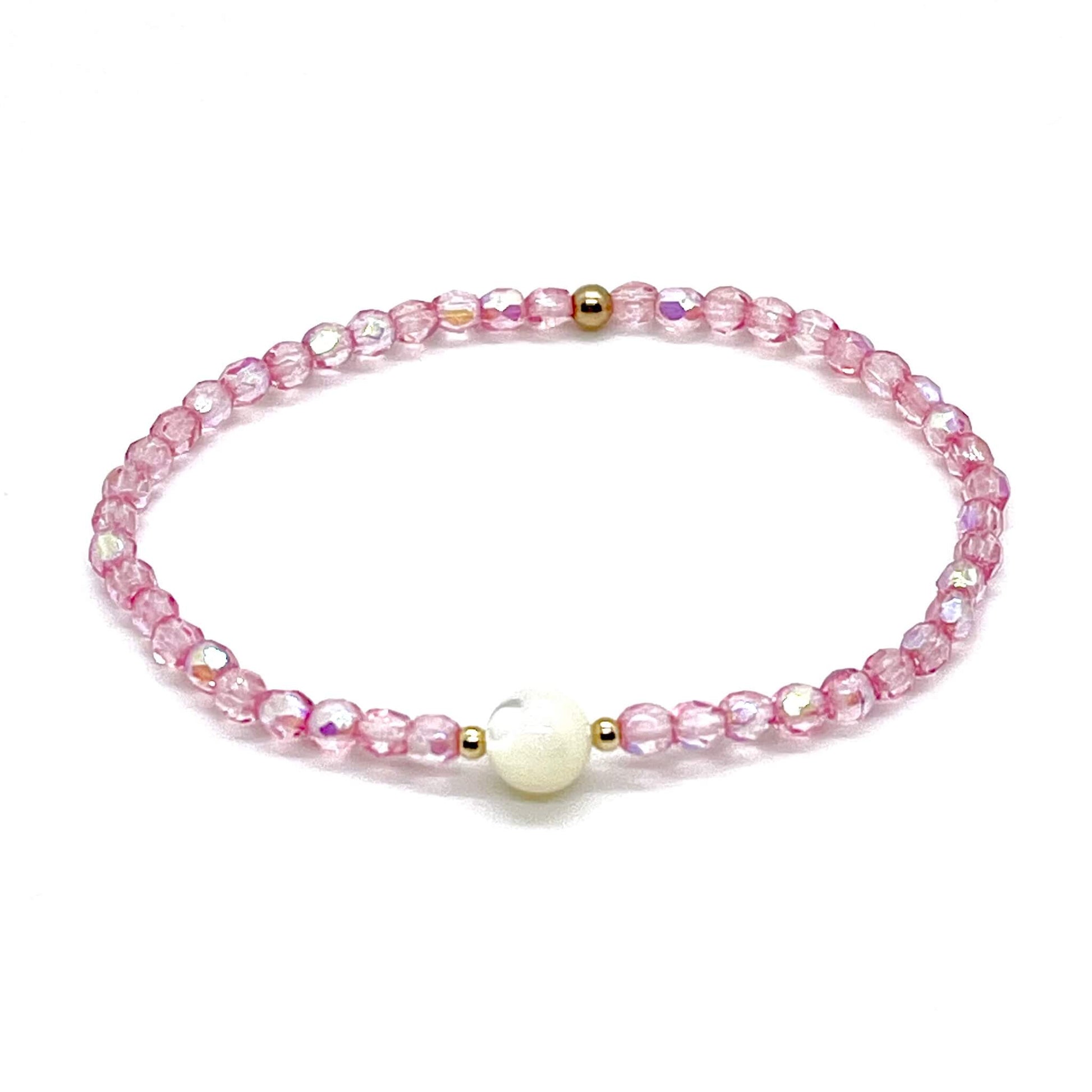 Pink crystal bracelet with a mother-of-pearl center bead and small gold accent beads.