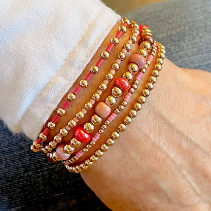 14K gold filled beaded ball set of 5 stackable elastic bracelets with colorful glass Miyuki beads in shades of pink & red.