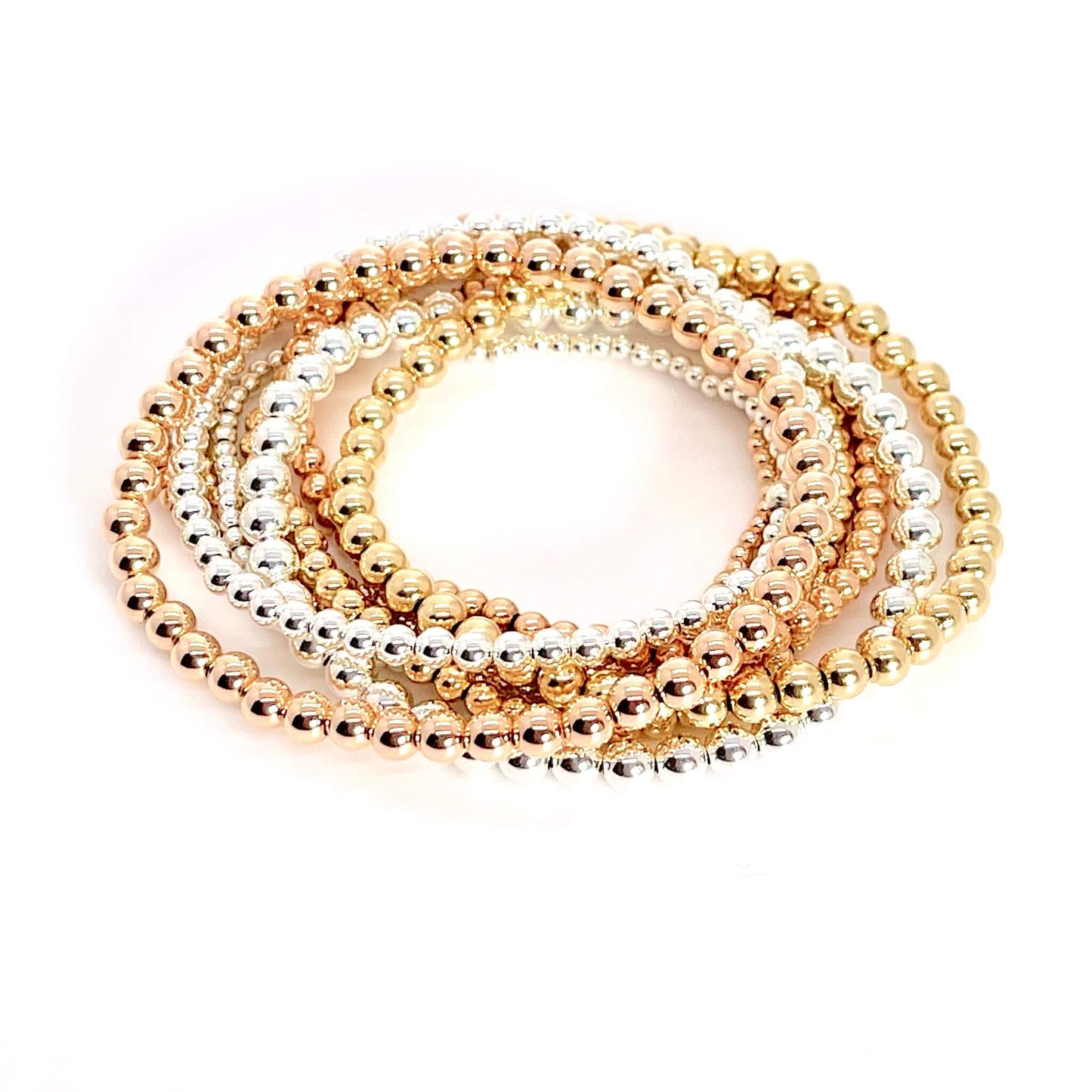 Rose gold, yellow gold, and silver beaded stretch bracelets stack.