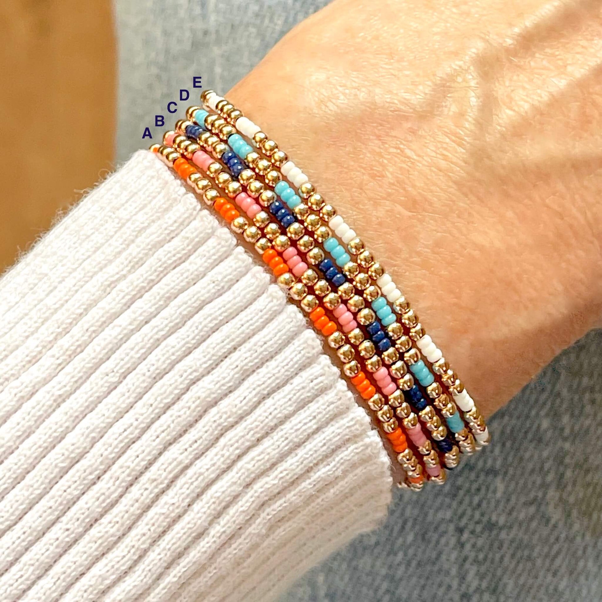 Small beaded stretch bracelets with colorful seed beads and rose gold 2mm beads. Available in orange, pink, blue, or white.
