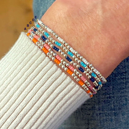 Small 2mm silver bead bracelets with colorful seed beads. Dainty beaded stretch bracelets for women with white, blue, pink, or orange beads.