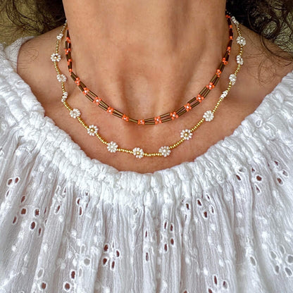 Seed bead necklace set with a brown and orange double strand necklace and a coordinating white and gold daisy chain necklace.