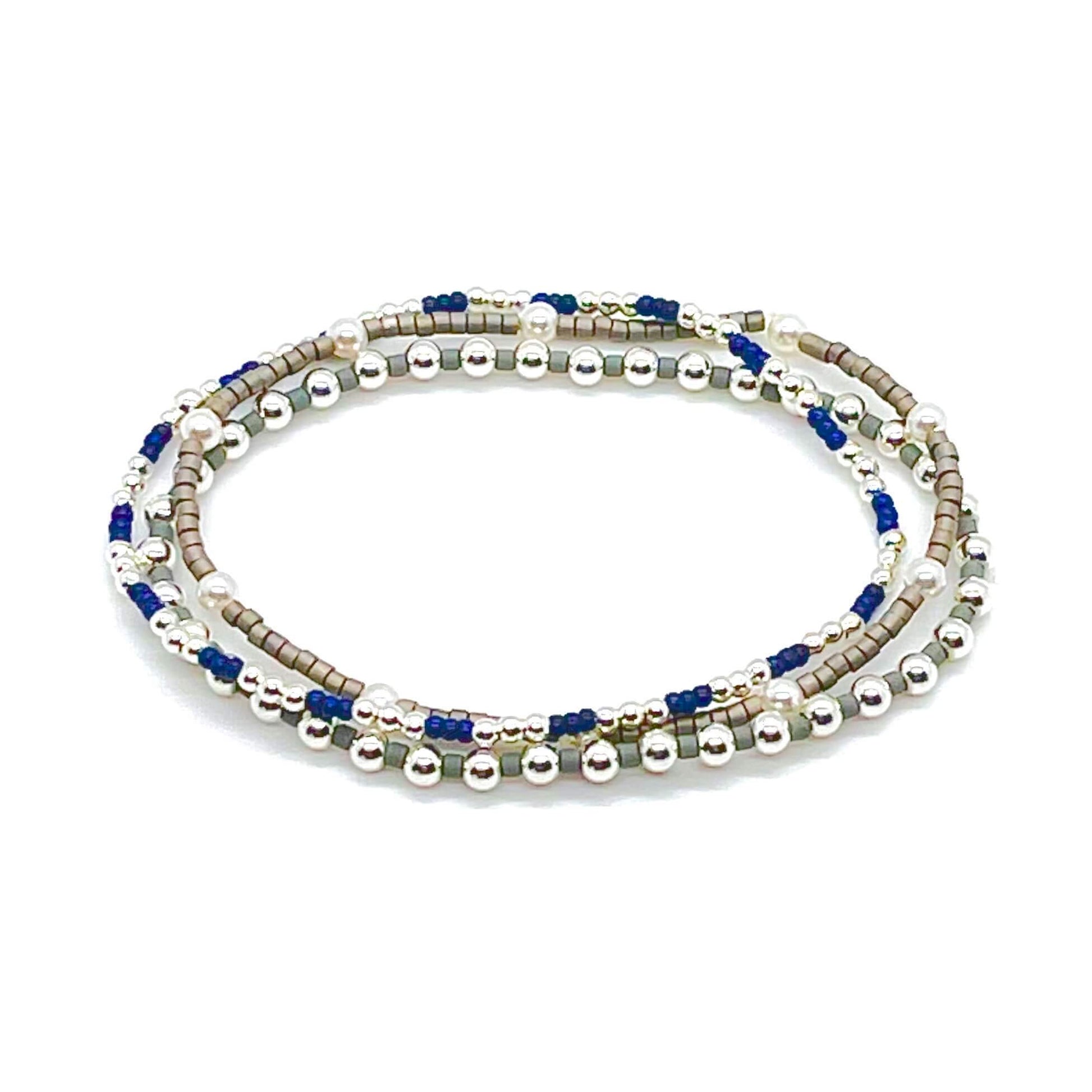 Silver beaded stretch bracelet trio with blue, grey, and pearl beads.
