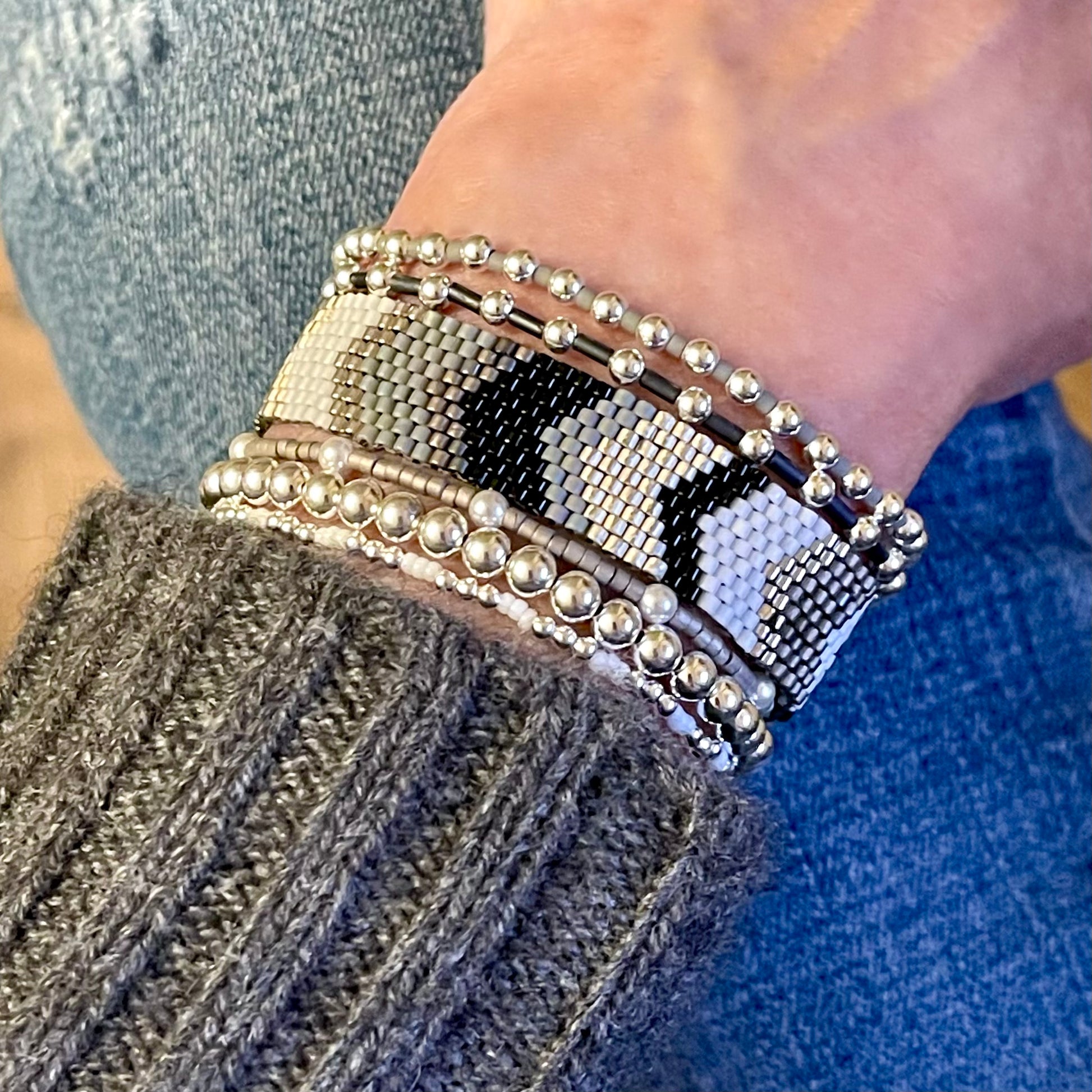 Silver, black, and white beaded bracelet stack with a chevron bracelet band and 5 silver stretch bracelets with seed beads and crystal pearl beads.