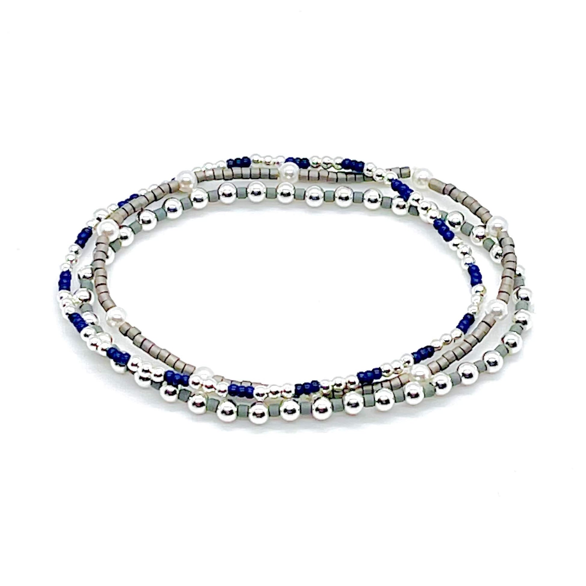 Silver bracelet stack with pearls, grey and blue seed beads, and silver ball beads on stretch cord.