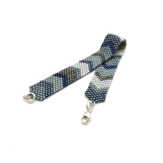 Sleek and modern metallic blue, slate, and gray hand woven beaded bracelet wristband with chevron-inspired details.