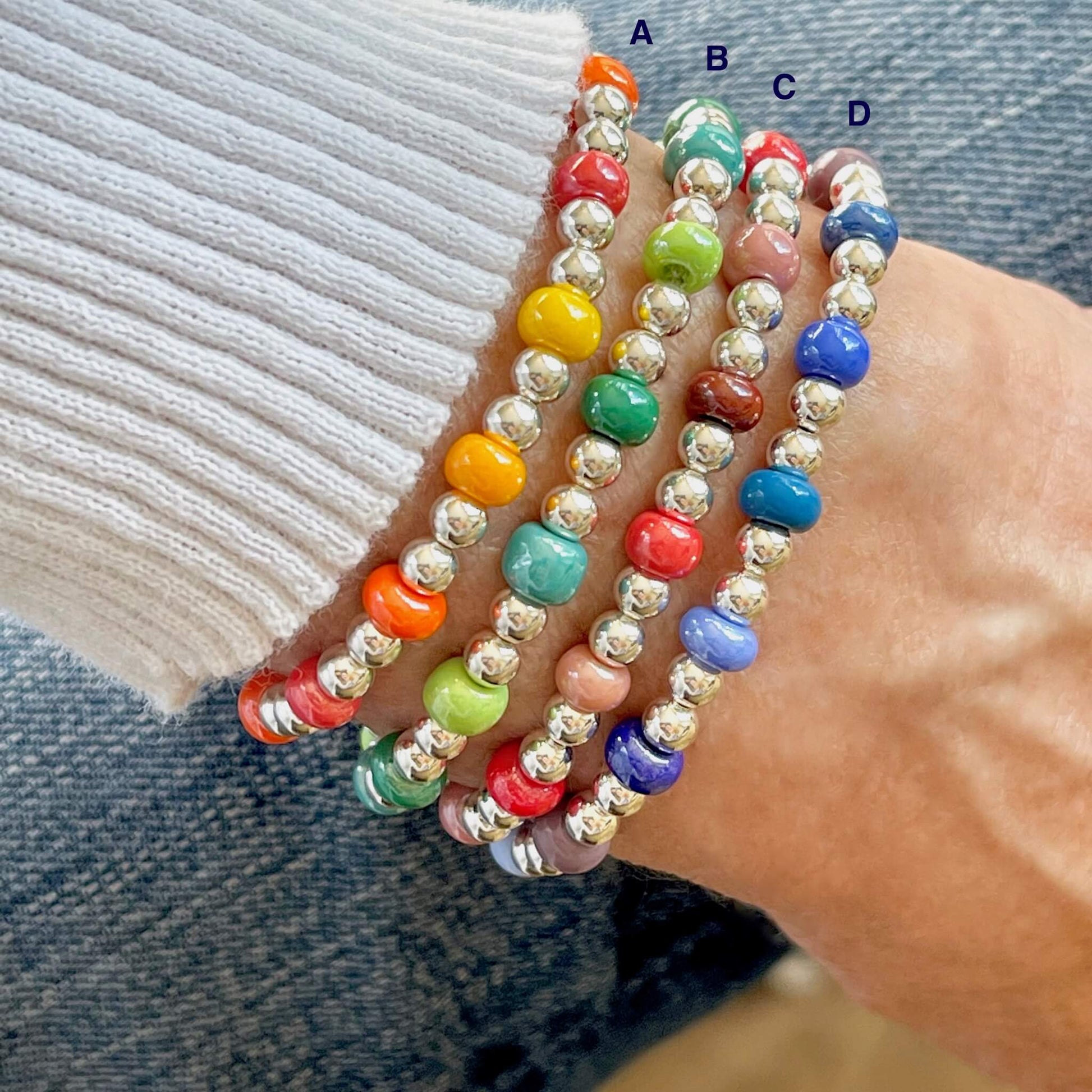 Sterling silver beaded bracelets with bright monochromatic color mixes of glass beads in reds, oranges, greens, and blues.