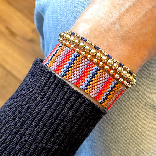 Striped beaded bracelet stack with blue, orange and gold beads in Southwestern hues. Woven and stretch beaded bracelet stack of 4.