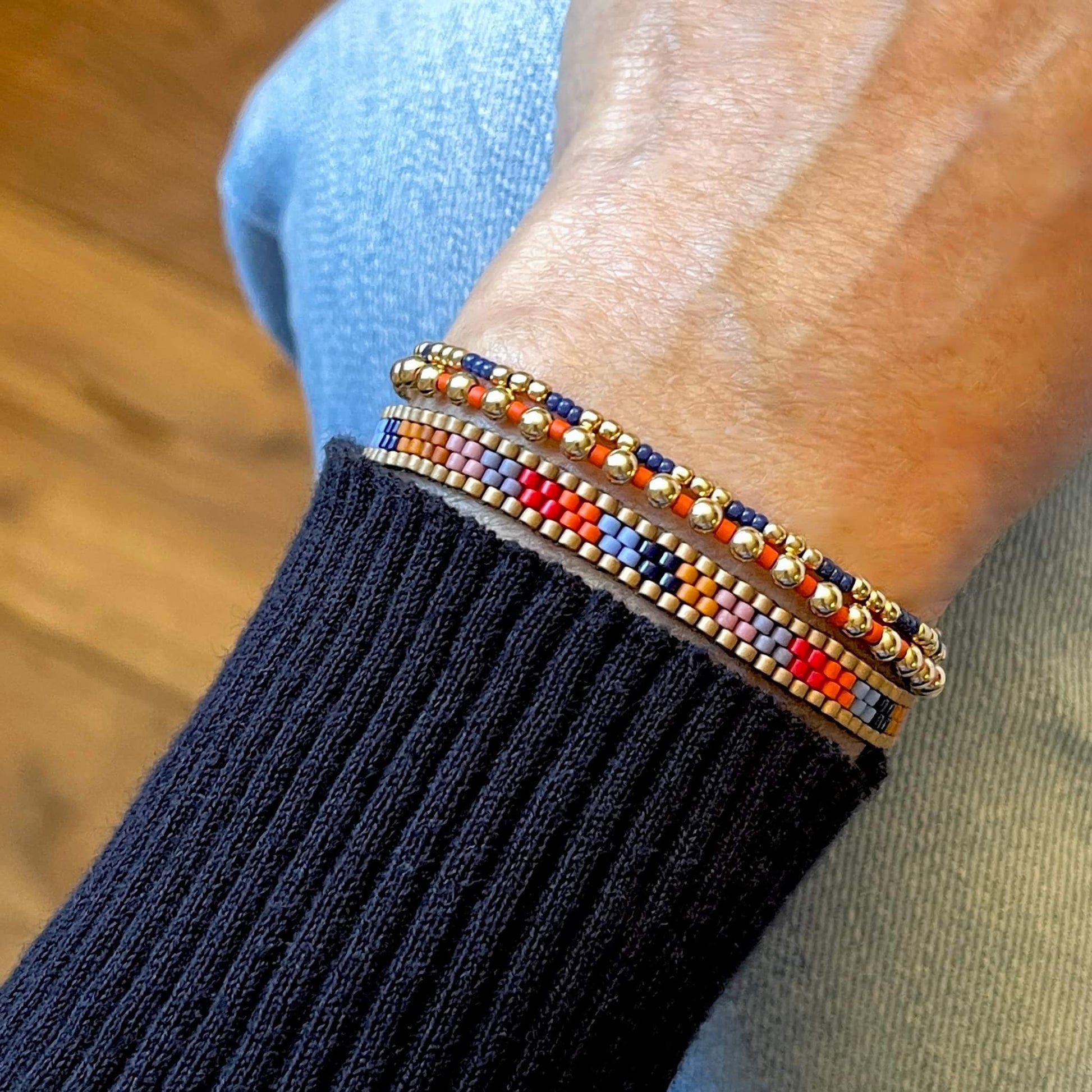 Thin beaded bracelet set with colorful striped band and orange and blue tiny seed bead stretch bracelets with gold ball beads.