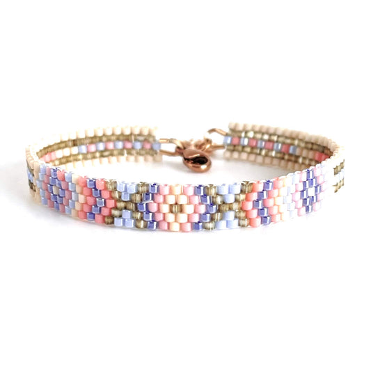 Hand beaded woven peyote bracelet with clasp in pastel blue, pink, and taupe seed beads in a pattern of diamonds and stripes.