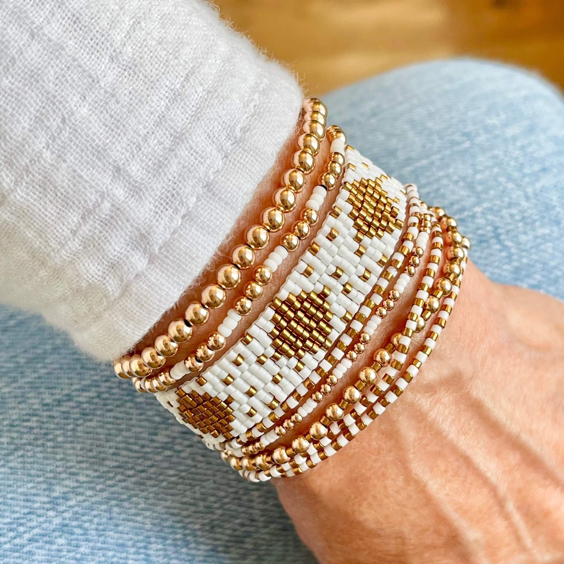 White bracelets with a handwoven seed bead cuff and wrap, and 14K rose gold filled stretch bracelets.