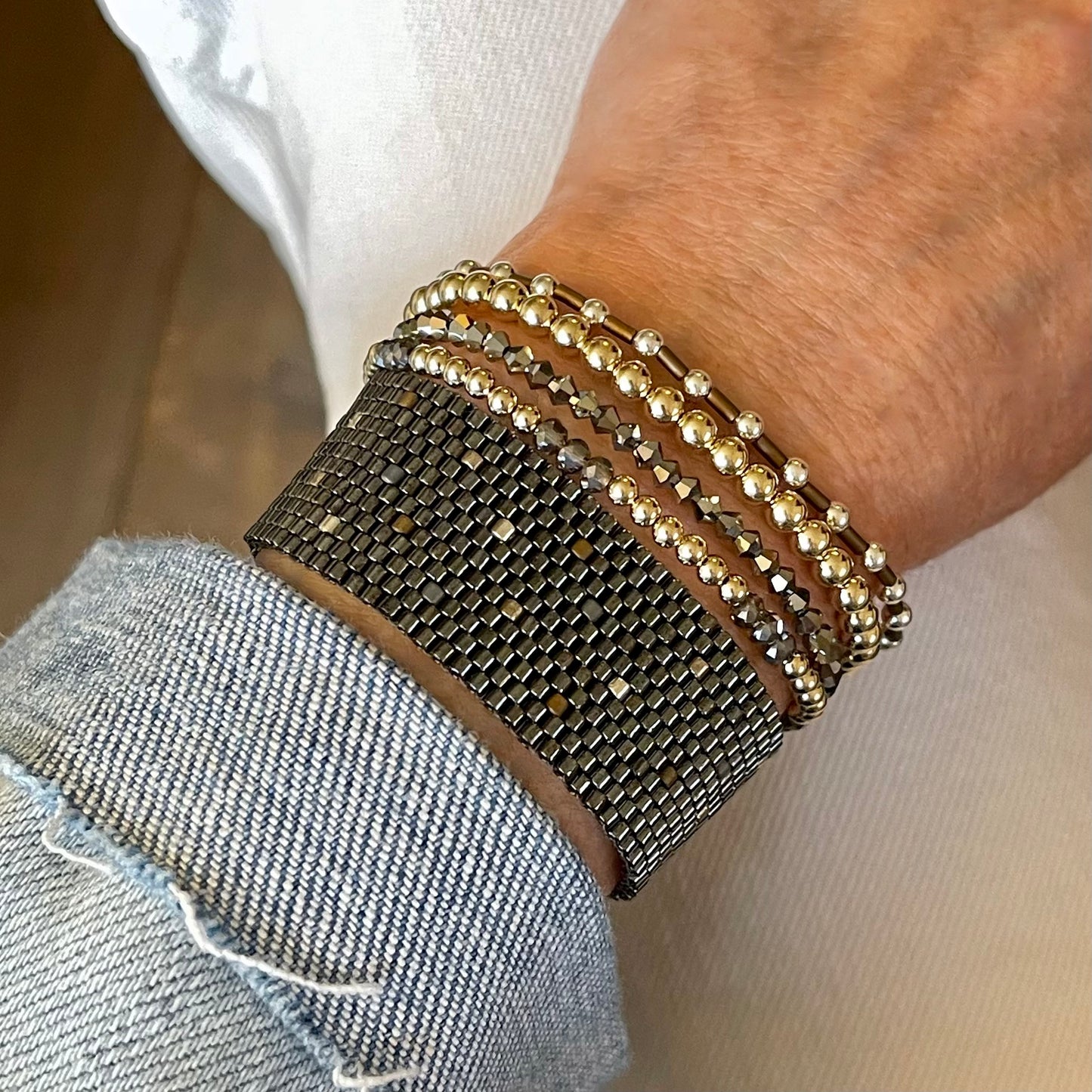 Wide gunmetal cuff and mixed metal bracelet stack. 14K gold filled, sterling silver, crystal, and bronze seed bead bracelets.