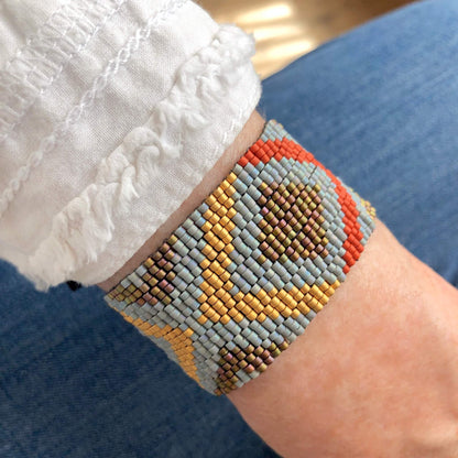 Wide peyote stitch bracelet with grey, gold, and orange seed beads.