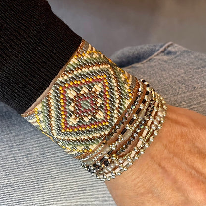 Wide woven beaded bracelet stack featuring a handmade seed bead cuff bracelet and silver, crystal, and seed bead stretch bracelets.