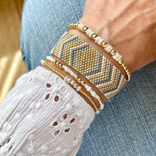 Flat beaded bracelet in gold, taupe, and white diamond and chevron peyote pattern, with 3 gold-filled, pearl, and heishi stretch bracelets.