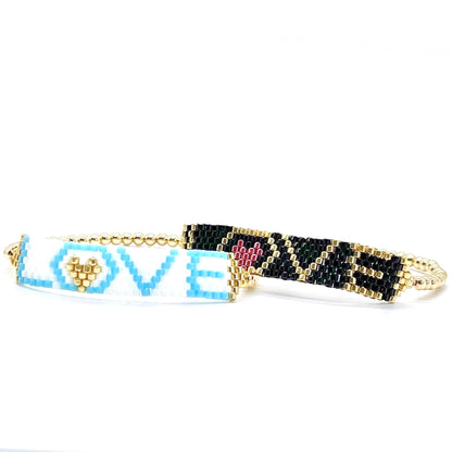 Stacking love bracelets with black, gold, white, and blue beads on gold stretch bracelets.