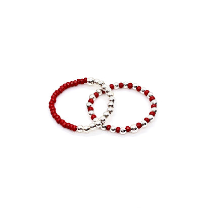 Stretch ring set with red color block and seed beads alternating with 2mm sterling silver balls on stretch cord.