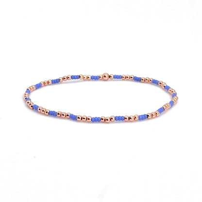 Rose gold bracelet for women with small periwinkle blue seed beads on stretch cord.