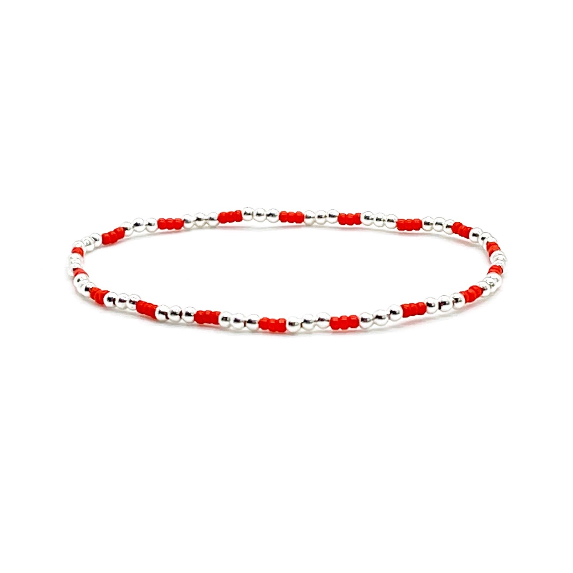 Red beaded bracelet with tiny 2mm sterling silver beads on elastic cord.