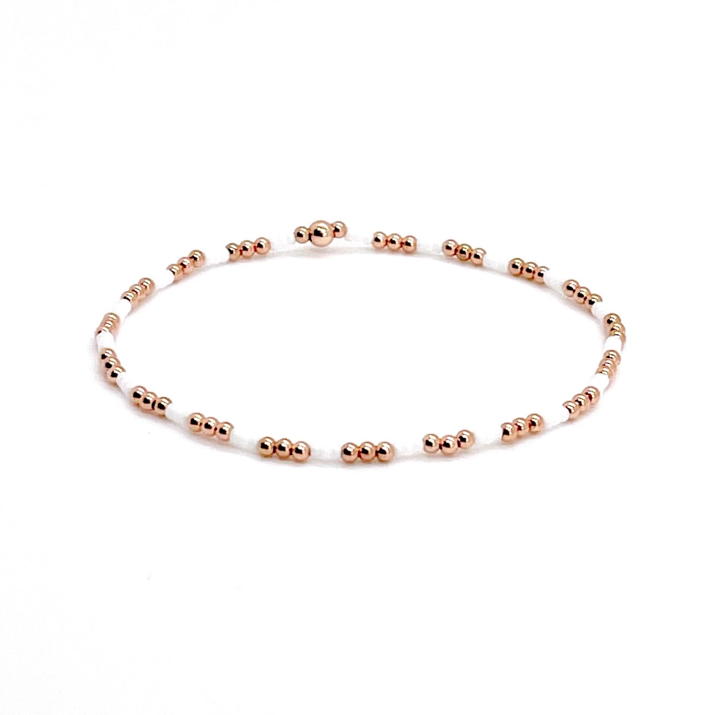 White bead bracelet with small 2mm rose gold beads on stretch cord.