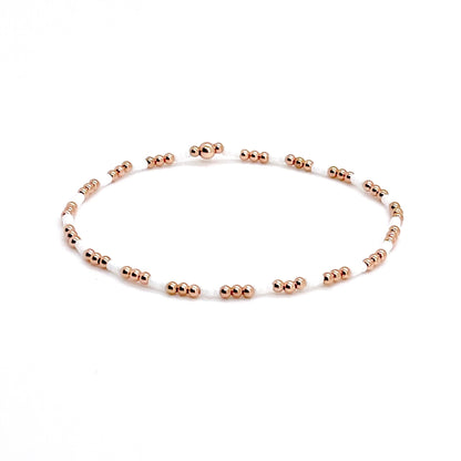 White bead bracelet with small 2mm rose gold beads on stretch cord.