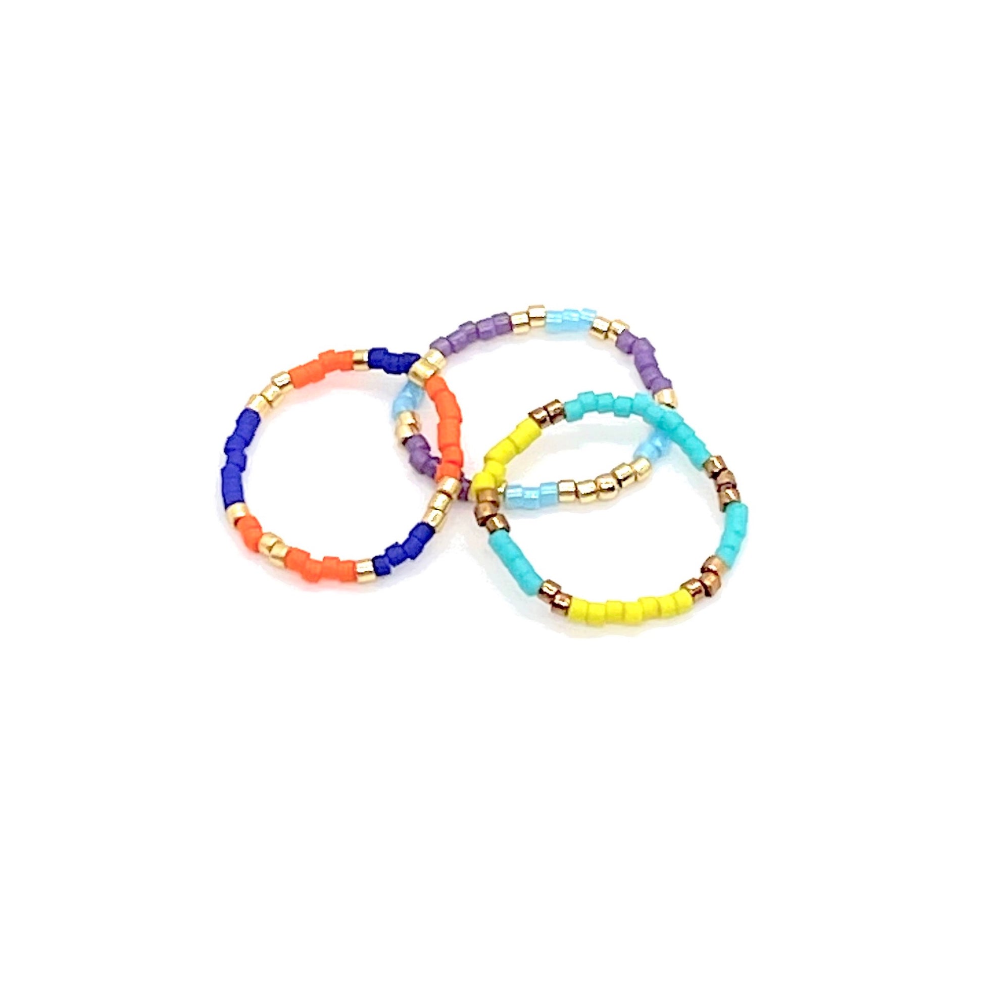 Beaded stretch ring set of 3 with color blocks of purple, blue, orange, yellow, and metal-tone Miyuki Delica seed beads.
