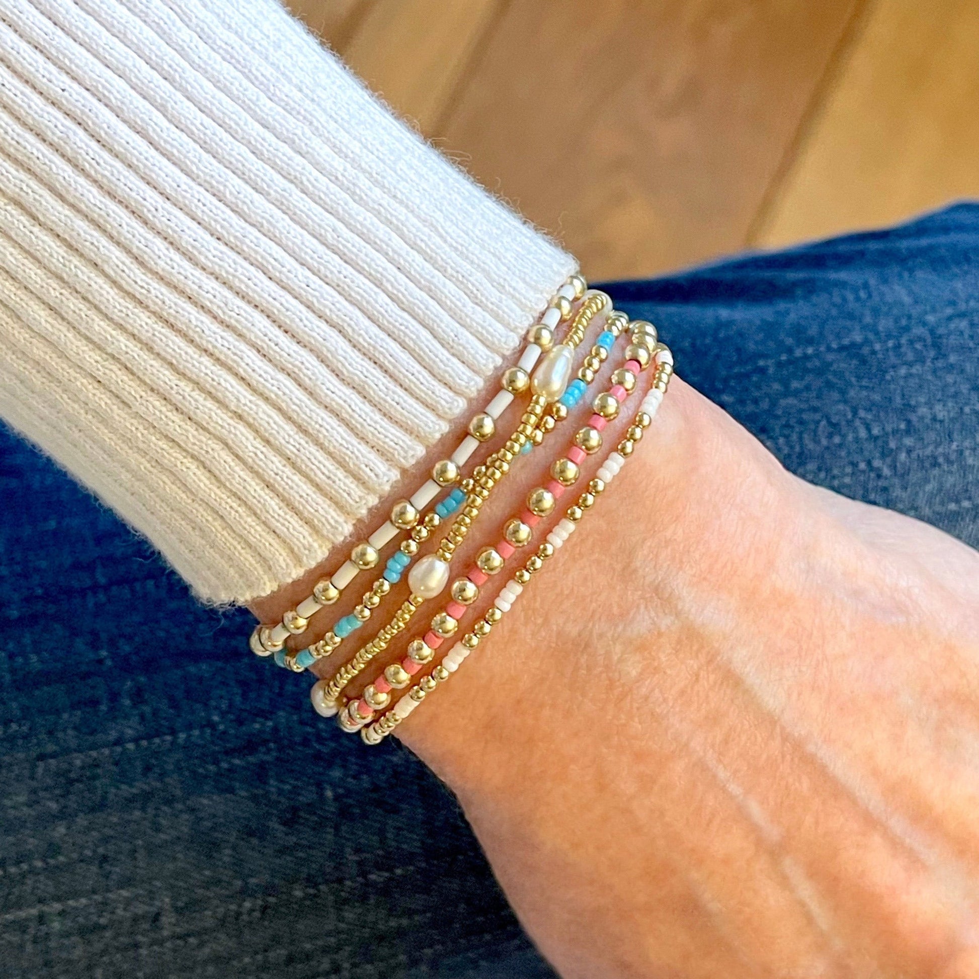 Stacked beaded bracelets with 14k gold fill balls, freshwater pearls, and pink, blue, and white seed beads. Stretch bracelets. Waterproof.