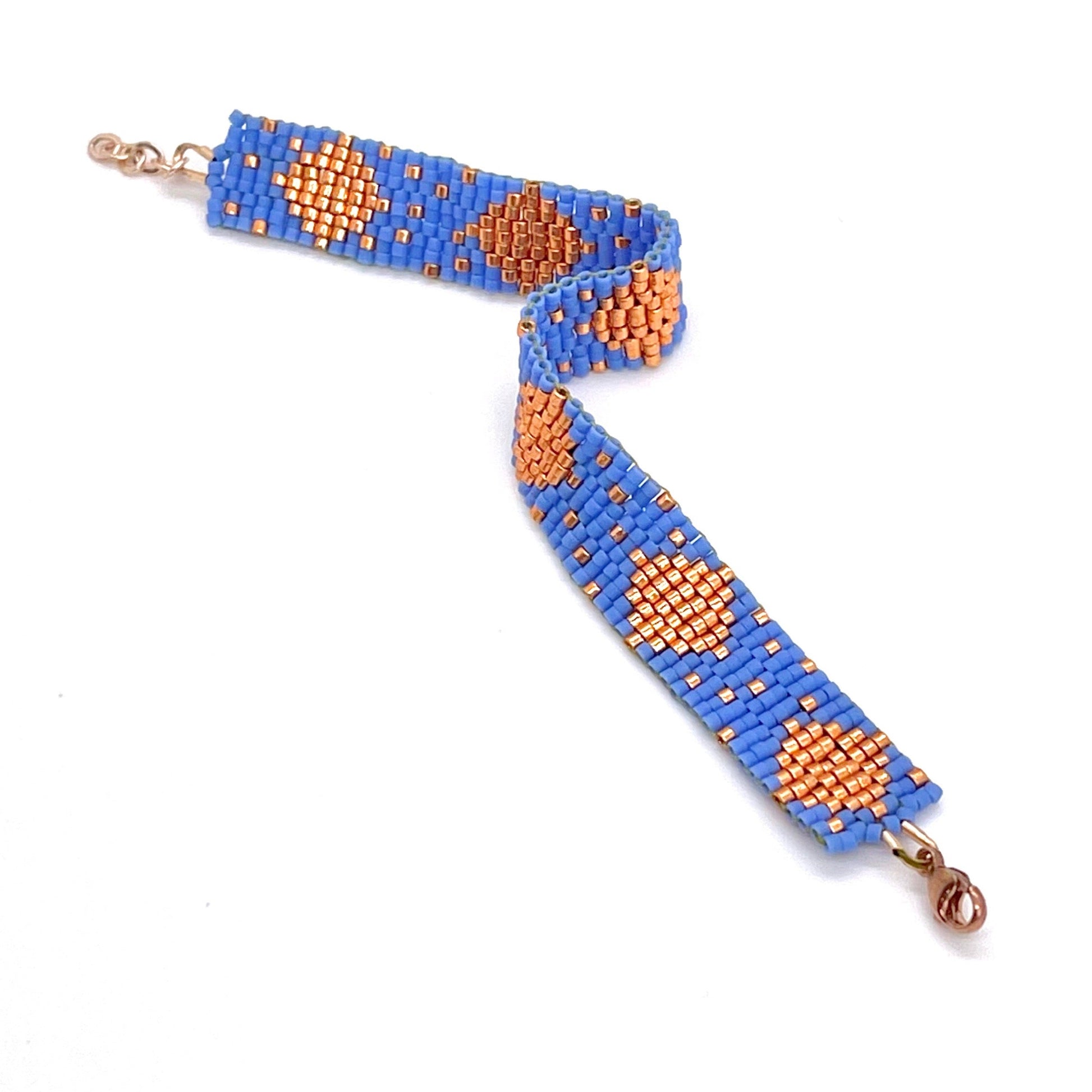 Two tone bracelet with periwinkle blue and rose gold-tone glass seed beads in a handwoven cuff with a diamond pattern.